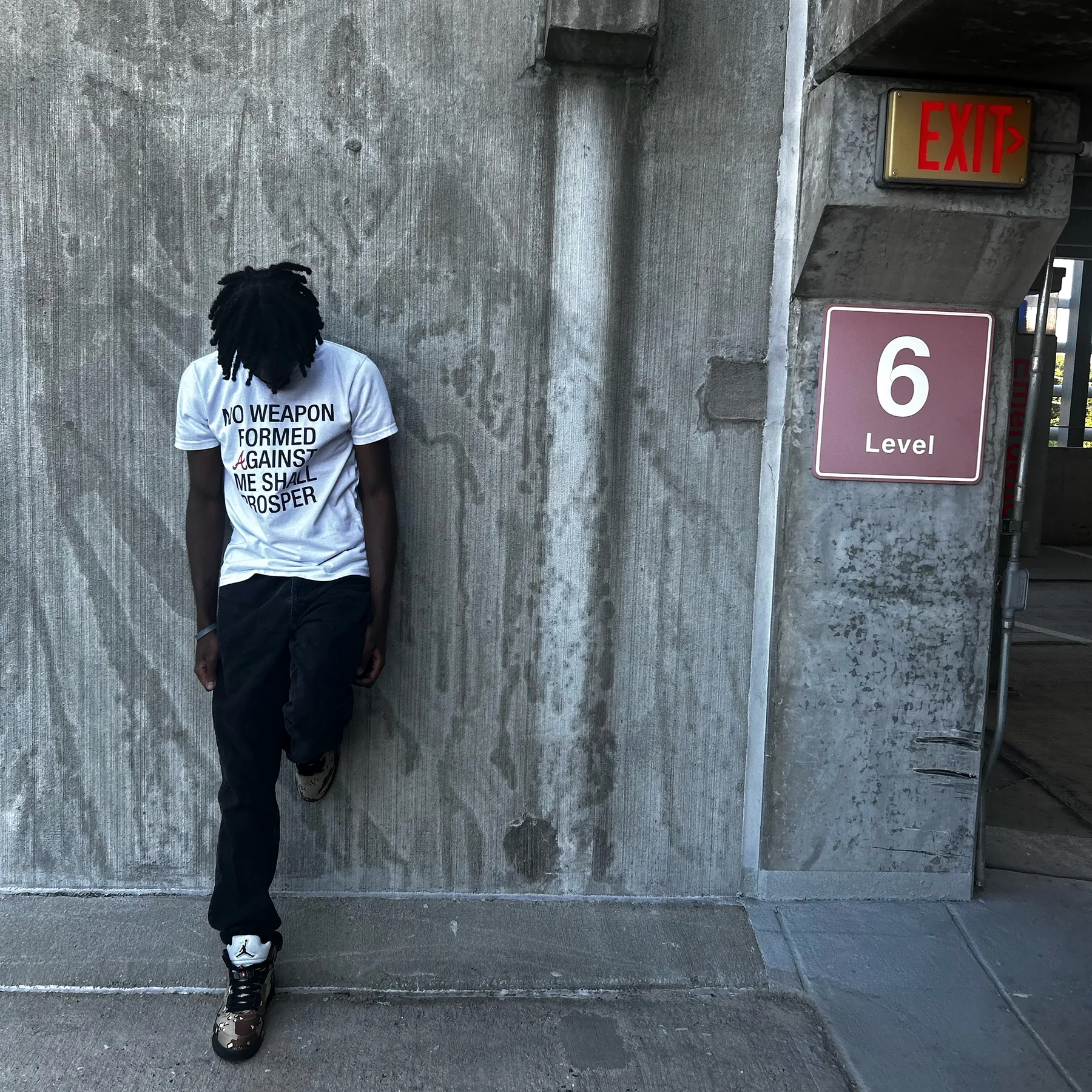 Mainetoowavy! against the concrete of a parking deck, a Level 6 sign beside him
